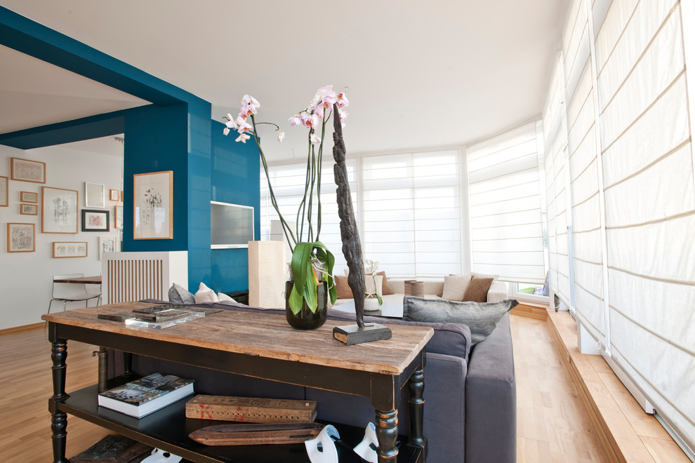 Ejemplo de salón con barra de bar abierto actual grande con paredes azules, suelo de madera en tonos medios, televisor colgado en la pared y suelo marrón
