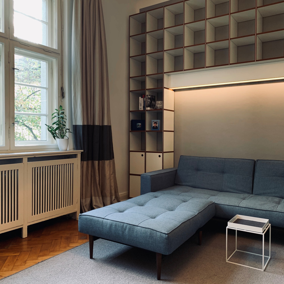 Идея дизайна: открытая гостиная комната среднего размера в современном стиле с с книжными шкафами и полками, серыми стенами, паркетным полом среднего тона, скрытым телевизором и бежевым полом без камина