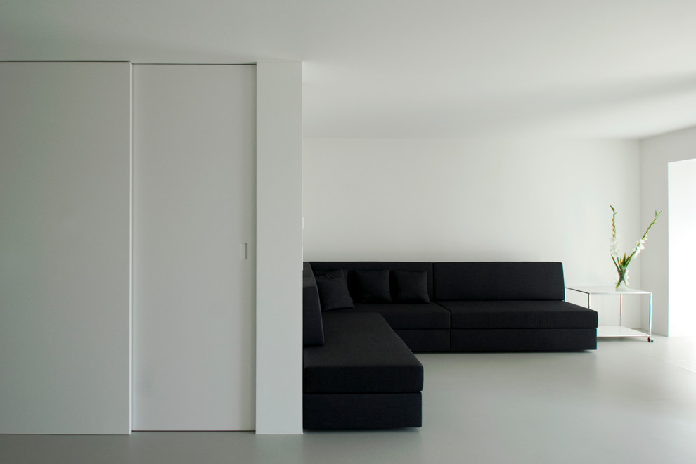 Offenes Wohnzimmer mit weißer Wandfarbe und Betonboden in Berlin