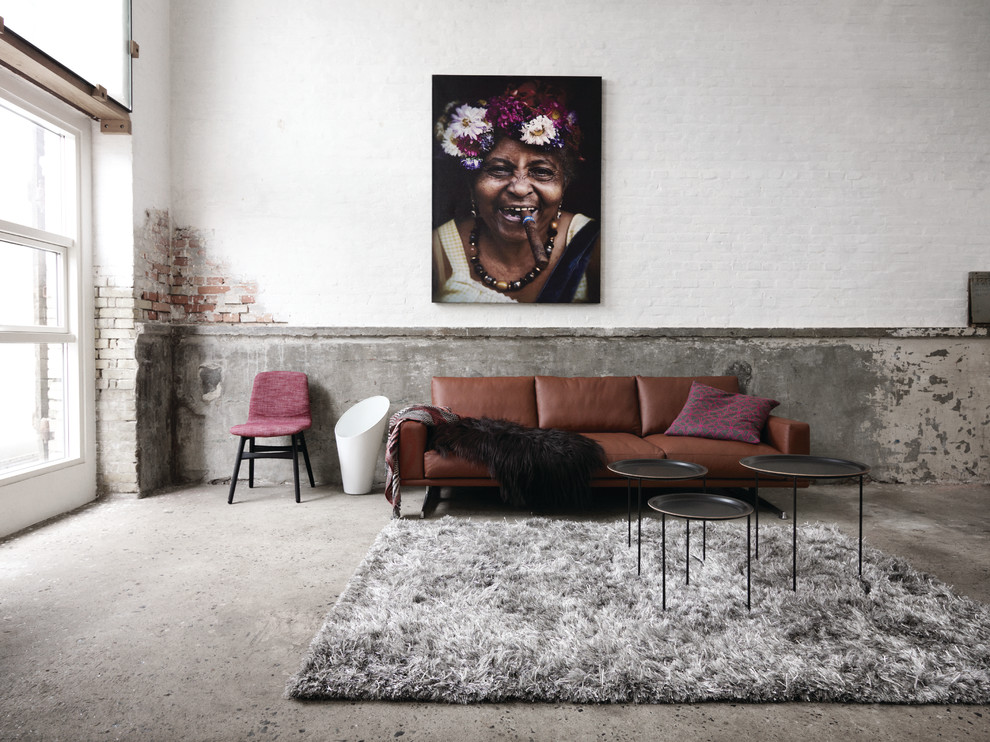 Diseño de sala de estar contemporánea sin chimenea con paredes blancas y suelo de cemento