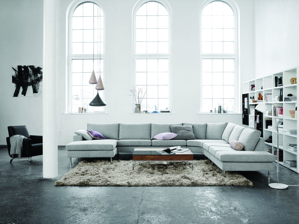 Modelo de sala de estar actual sin chimenea y televisor con paredes blancas y suelo de cemento