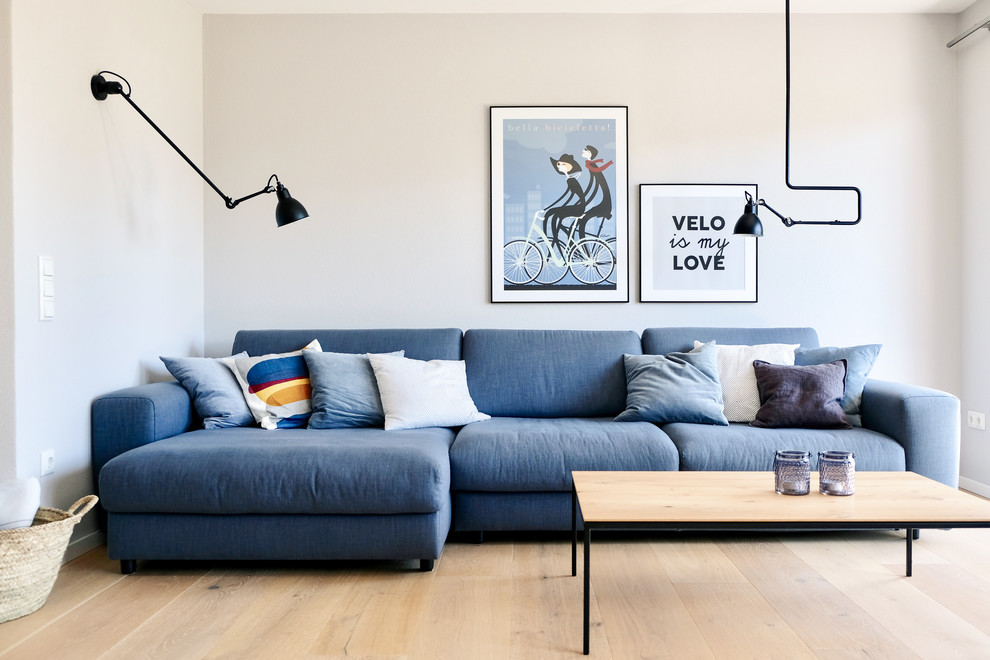Bild på ett mellanstort minimalistiskt allrum med öppen planlösning, med grå väggar och ljust trägolv