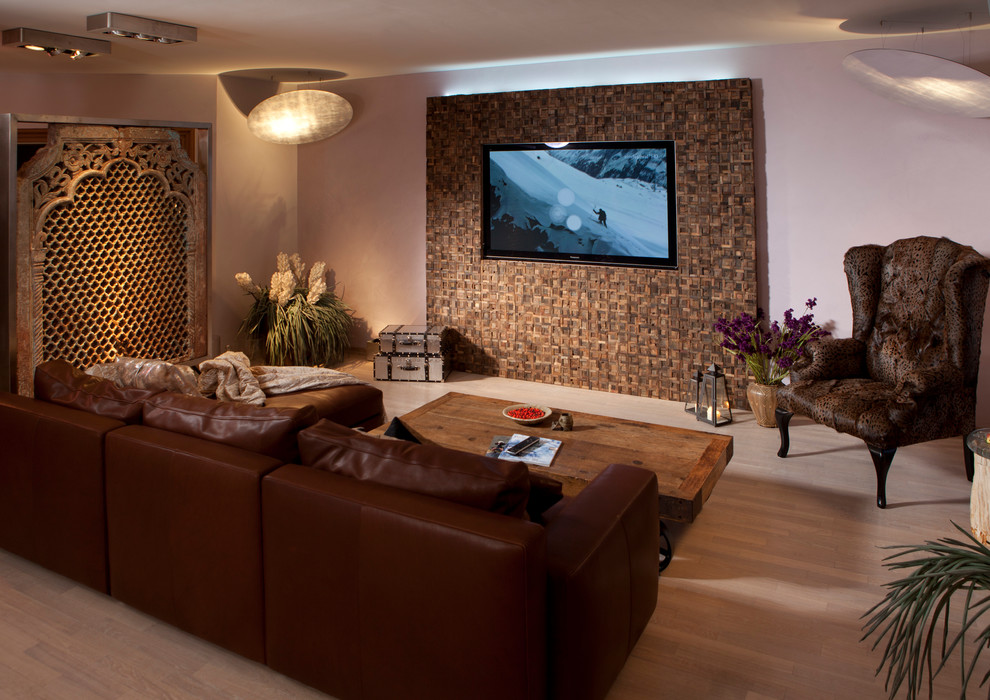 Aménagement d'une grande salle de séjour exotique ouverte avec un mur multicolore, parquet clair et un téléviseur encastré.
