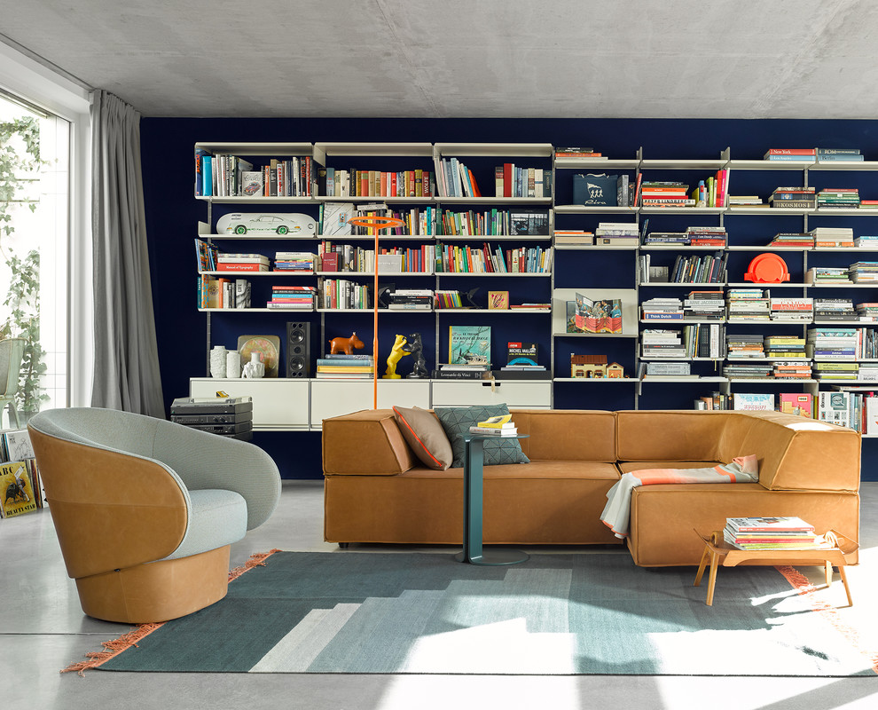 Ispirazione per un soggiorno minimalista di medie dimensioni e chiuso con libreria, pareti blu, pavimento in cemento, nessun camino, nessuna TV e pavimento grigio