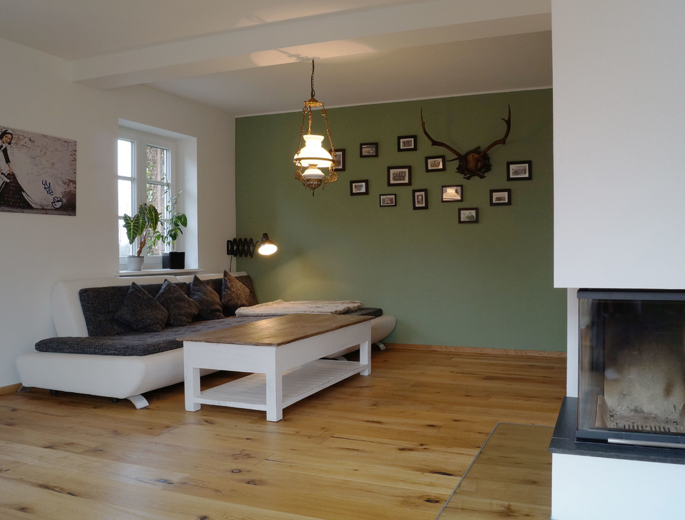 Idée de décoration pour une salle de séjour design de taille moyenne et ouverte avec un mur vert, parquet peint, une cheminée d'angle, un manteau de cheminée en plâtre, un téléviseur fixé au mur et un sol marron.
