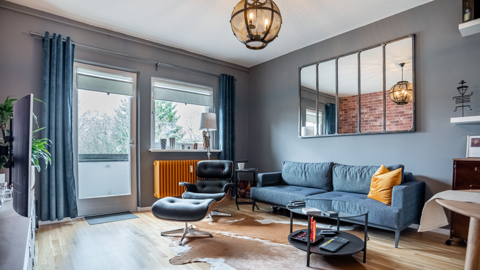 Свежая идея для дизайна: гостиная комната в стиле лофт с серыми стенами, паркетным полом среднего тона и коричневым полом - отличное фото интерьера
