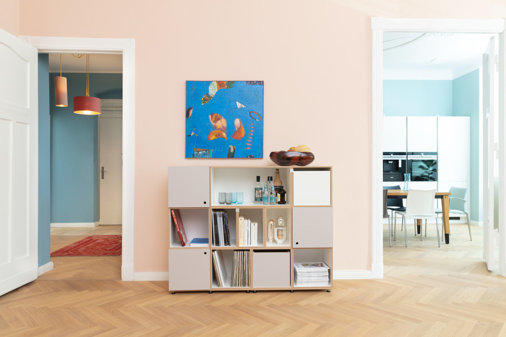 Imagen de sala de estar cerrada contemporánea sin televisor con paredes rosas, suelo de madera en tonos medios y suelo marrón