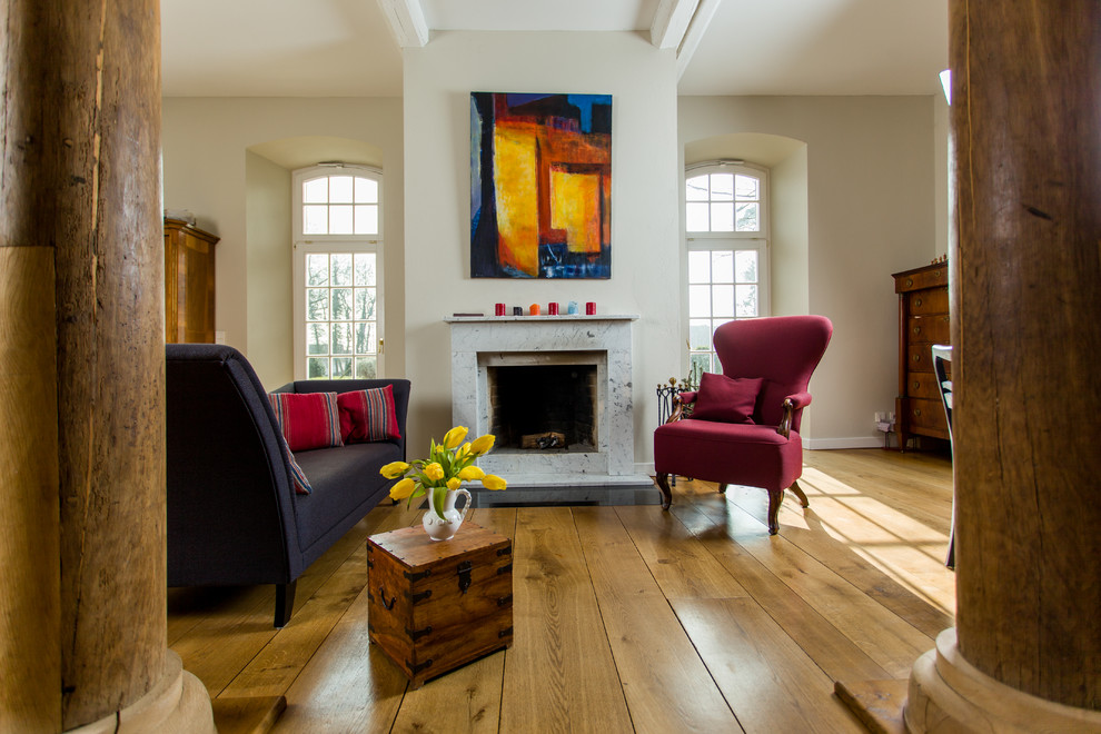 Imagen de sala de estar abierta contemporánea grande sin televisor con paredes beige, suelo de madera clara, estufa de leña, marco de chimenea de piedra y suelo marrón