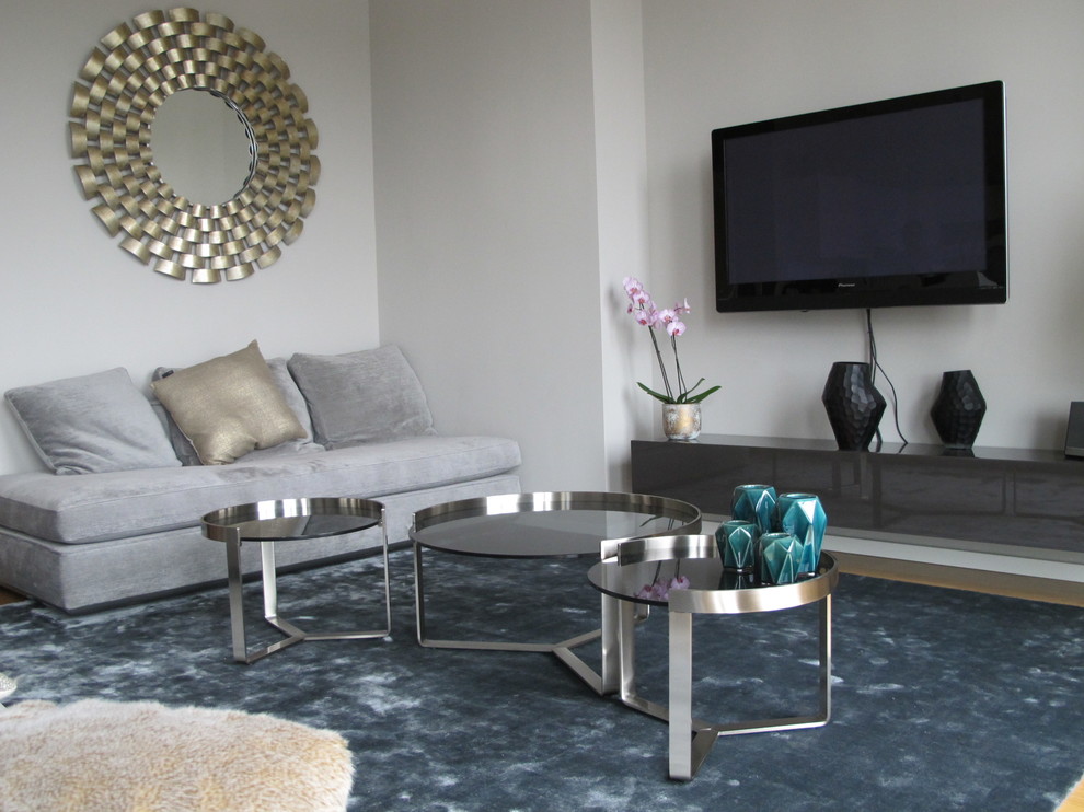 На фото: большая открытая гостиная комната в современном стиле с серыми стенами, ковровым покрытием и телевизором на стене