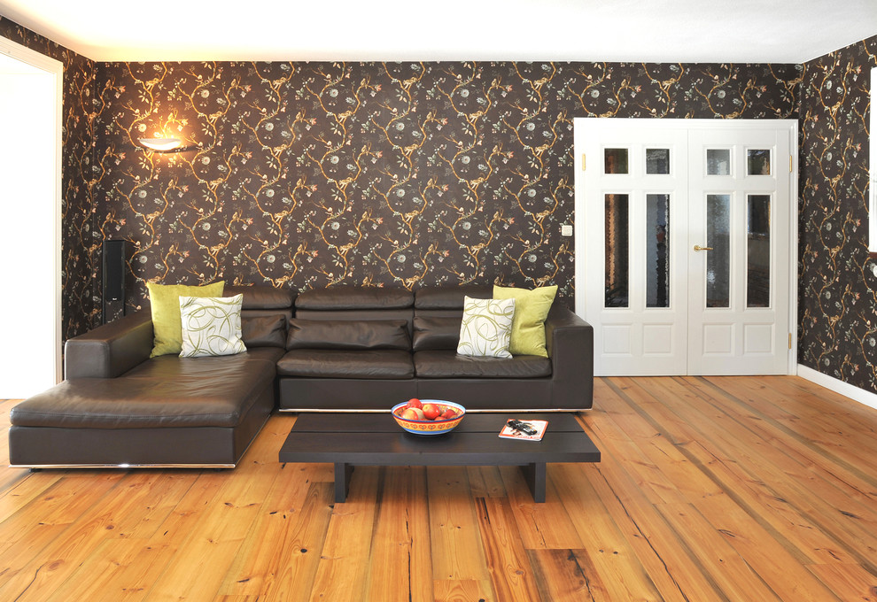 Imagen de sala de estar con biblioteca abierta de estilo de casa de campo grande sin chimenea y televisor con suelo de madera en tonos medios y paredes multicolor