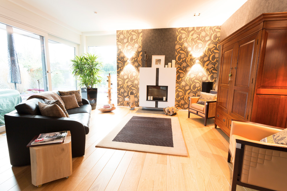 デュッセルドルフにある高級な広いコンテンポラリースタイルのおしゃれなオープンリビング (無垢フローリング、標準型暖炉、漆喰の暖炉まわり、内蔵型テレビ、マルチカラーの壁、茶色い床) の写真