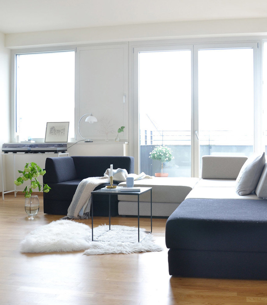 Стильный дизайн: большая открытая гостиная комната в скандинавском стиле с белыми стенами, коричневым полом, паркетным полом среднего тона, телевизором на стене и музыкальной комнатой - последний тренд