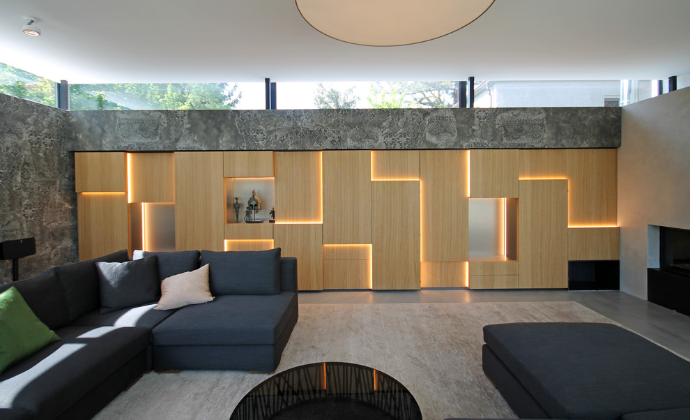 Großes, Offenes Modernes Wohnzimmer mit grauer Wandfarbe, Betonboden, Kamin, Kaminumrandung aus Beton, verstecktem TV und grauem Boden in München