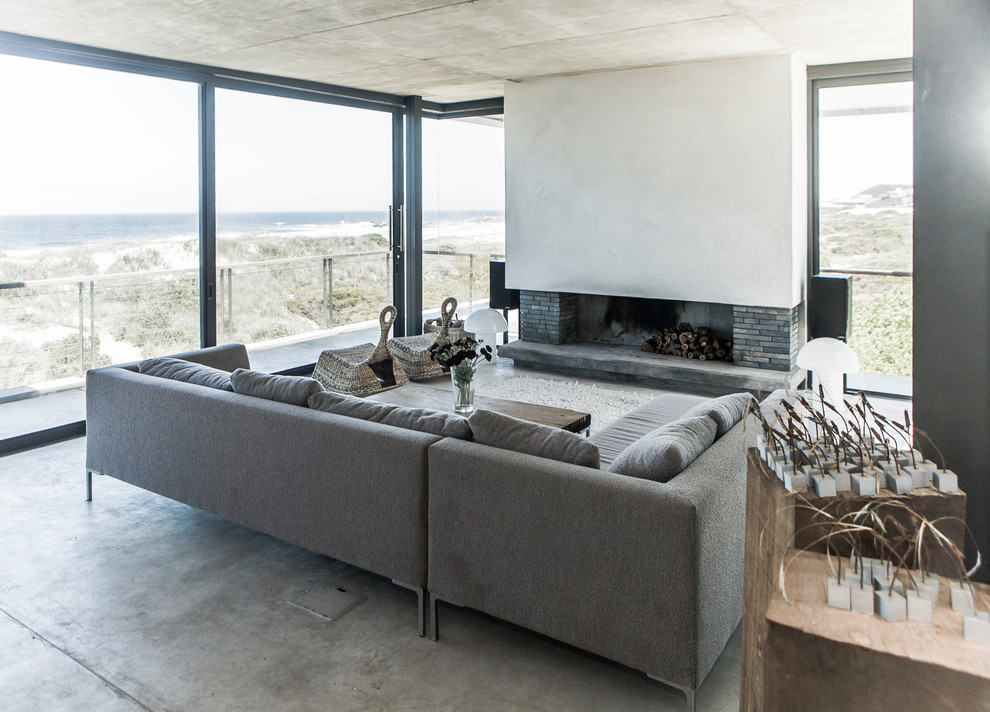 Réalisation d'un salon design de taille moyenne avec une salle de réception, un mur blanc, sol en béton ciré, un poêle à bois, un manteau de cheminée en plâtre et un sol gris.