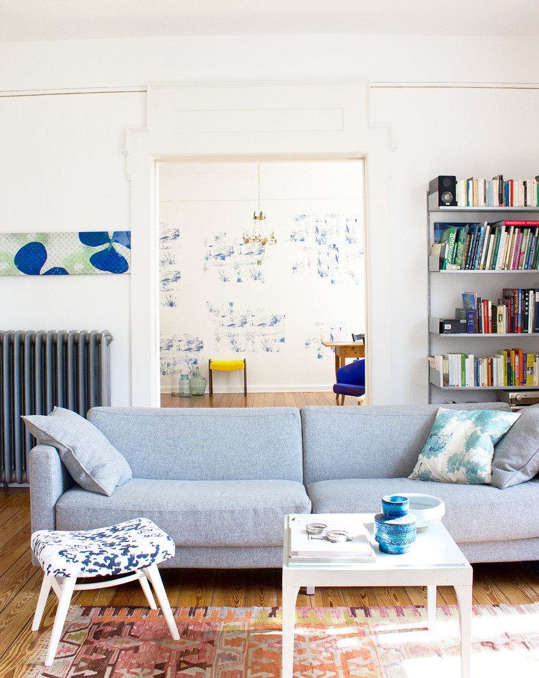 Inspiration pour un salon bohème fermé avec une bibliothèque ou un coin lecture, un mur blanc et un sol en bois brun.