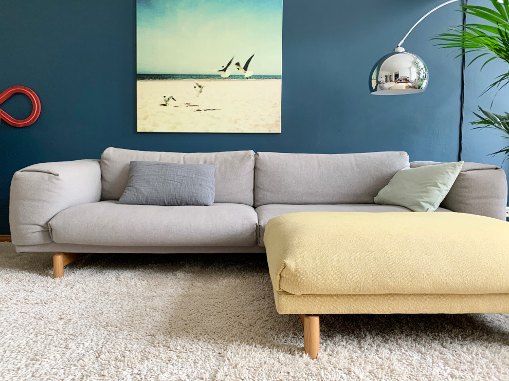 Aménagement d'une grande salle de séjour contemporaine ouverte avec un bar de salon, un mur bleu, un sol en bois brun, un téléviseur fixé au mur et un sol marron.