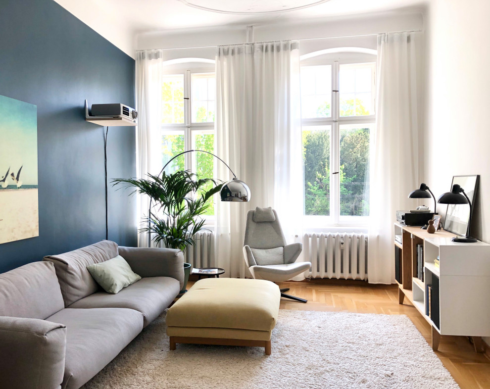 Großes, Offenes Modernes Wohnzimmer mit Hausbar, blauer Wandfarbe, braunem Holzboden, TV-Wand und braunem Boden in Berlin