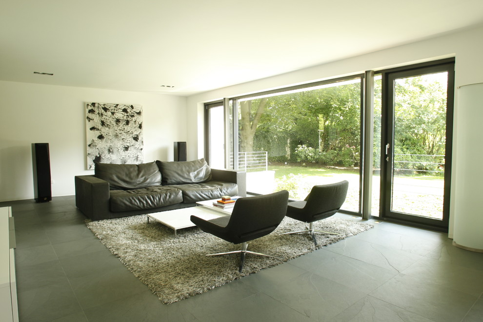 Immagine di un grande soggiorno contemporaneo con pareti bianche e pavimento in ardesia