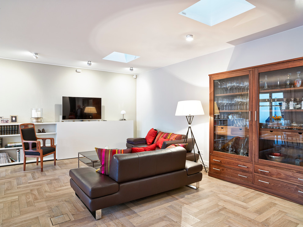 Foto de sala de estar abierta actual de tamaño medio sin chimenea con paredes grises, televisor colgado en la pared y suelo de madera en tonos medios