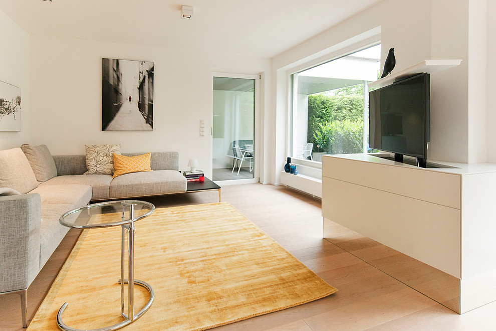 Idee per un soggiorno minimal di medie dimensioni e aperto con pareti bianche, parquet chiaro, TV nascosta e pavimento marrone