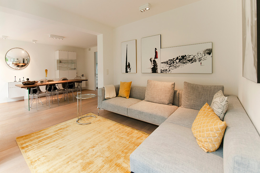 Exemple d'une salle de séjour tendance de taille moyenne et ouverte avec un mur blanc, parquet clair, un téléviseur dissimulé et un sol marron.