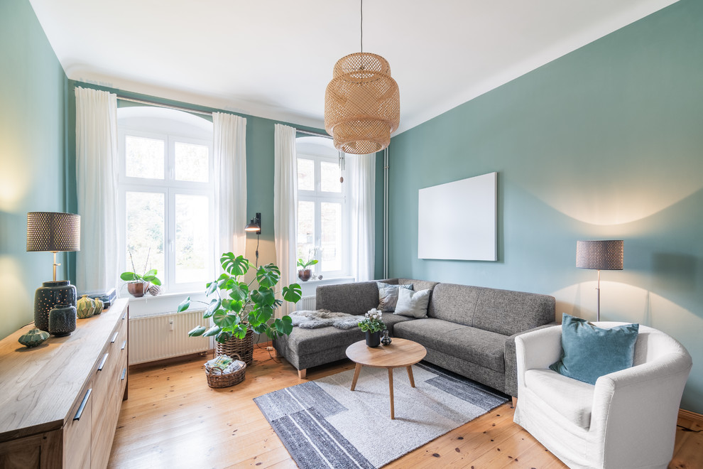 Großes Nordisches Wohnzimmer mit grüner Wandfarbe und braunem Holzboden in Berlin