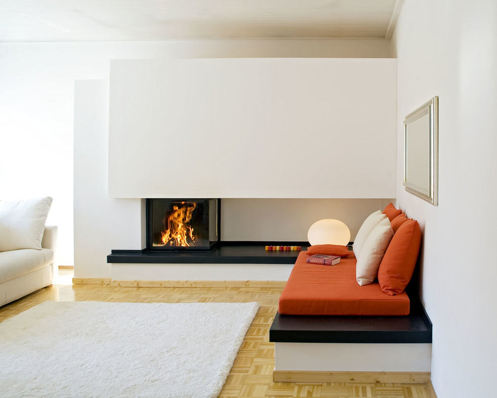 This is an example of a modern living room in Cologne with white walls, painted wood flooring, a corner fireplace and a plastered fireplace surround.
