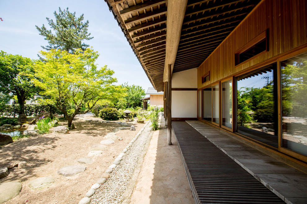 Aménagement d'une terrasse arrière asiatique avec une extension de toiture.