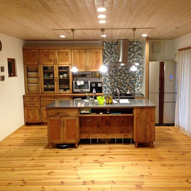 Idéer för att renovera ett mellanstort amerikanskt brun brunt kök, med en integrerad diskho, luckor med profilerade fronter, skåp i mellenmörkt trä, bänkskiva i rostfritt stål, brunt stänkskydd, stänkskydd i trä, rostfria vitvaror, ljust trägolv, en köksö och beiget golv