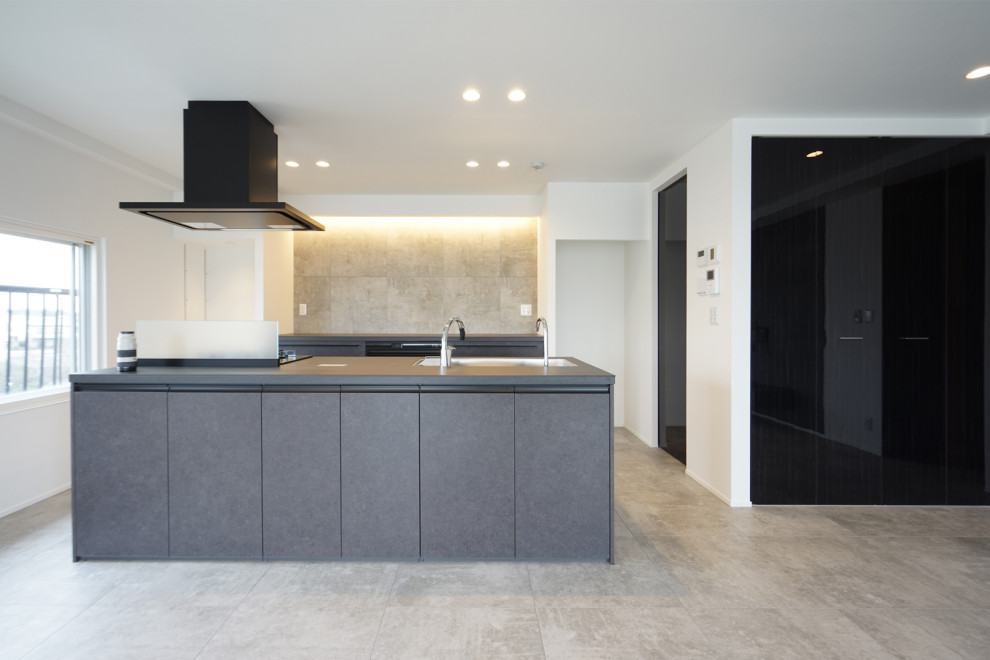 Cette image montre une grande cuisine ouverte linéaire et grise et noire minimaliste avec un évier 1 bac, îlot, un sol gris et un plafond en papier peint.