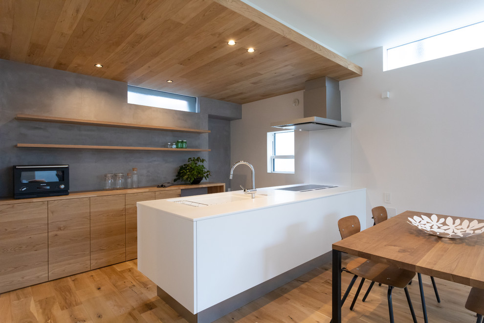 Стильный дизайн: прямая кухня-гостиная в стиле модернизм с монолитной мойкой, плоскими фасадами, фасадами цвета дерева среднего тона, паркетным полом среднего тона, полуостровом и коричневым полом - последний тренд