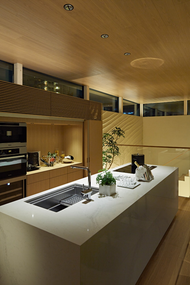 Cette photo montre une cuisine ouverte linéaire moderne avec un évier encastré, des portes de placard blanches, un plan de travail en quartz modifié, un électroménager en acier inoxydable, un sol en travertin, îlot, un sol beige et un plan de travail beige.