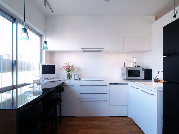Offene, Mittelgroße Shabby-Style Küche ohne Insel in L-Form mit Einbauwaschbecken, flächenbündigen Schrankfronten, weißen Schränken, Küchenrückwand in Weiß, weißen Elektrogeräten und braunem Holzboden in Tokio