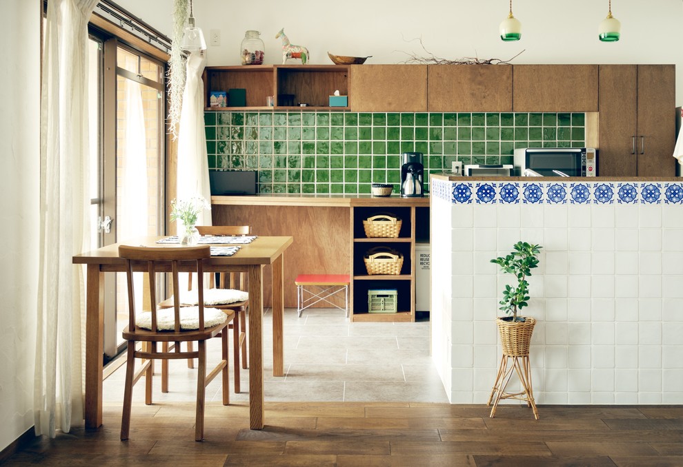 Zweizeilige, Kleine Country Wohnküche mit flächenbündigen Schrankfronten, hellbraunen Holzschränken, Küchenrückwand in Grün, Rückwand aus Porzellanfliesen und braunem Holzboden in Nagoya