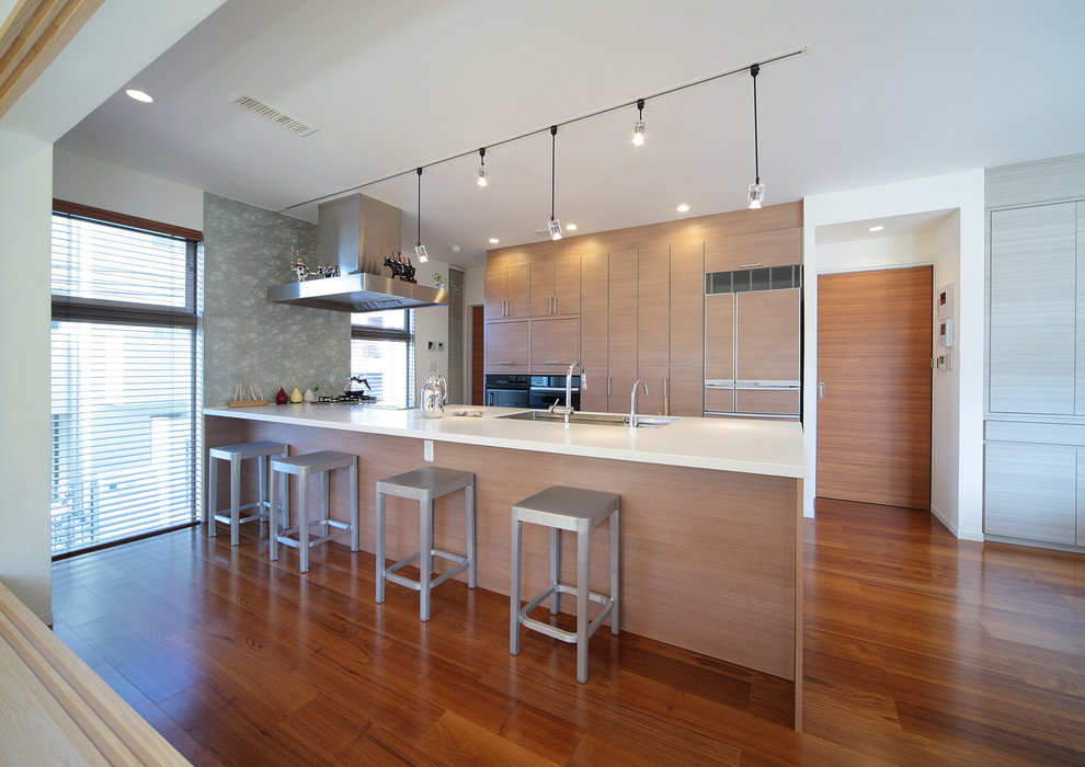 Contemporary single-wall kitchen in Tokyo with flat-panel cabinets, beige cabinets, medium hardwood flooring, a breakfast bar, brown floors and white worktops.