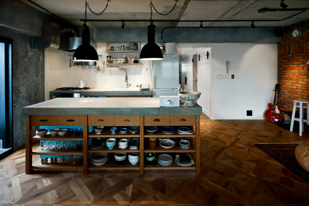 東京23区にあるインダストリアルスタイルのおしゃれなアイランドキッチン (ドロップインシンク、中間色木目調キャビネット、コンクリートカウンター、白いキッチンパネル、無垢フローリング、茶色い床) の写真
