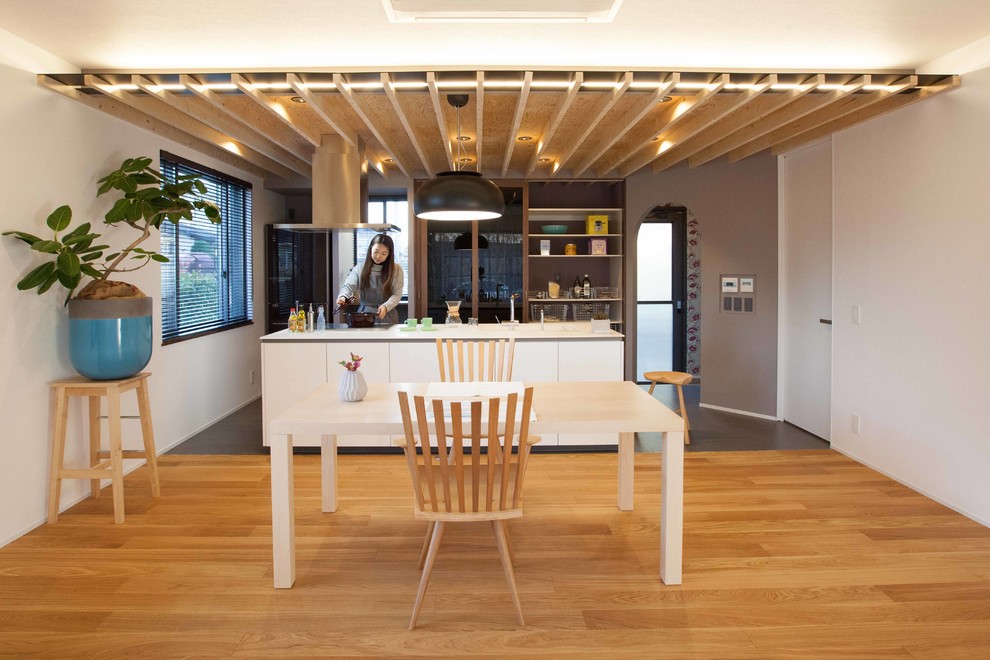 Cette photo montre une grande cuisine ouverte linéaire scandinave avec des portes de placard blanches, un plan de travail en surface solide, carreaux de ciment au sol, îlot et un sol noir.