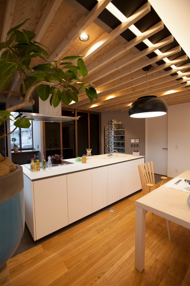 Diseño de cocina lineal escandinava grande abierta con encimera de acrílico, suelo de azulejos de cemento, una isla, suelo negro y puertas de armario blancas