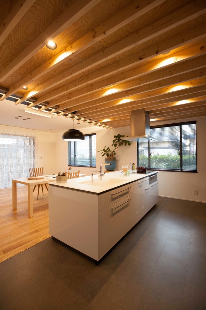 Foto på ett stort funkis linjärt kök med öppen planlösning, med vita skåp, bänkskiva i koppar, cementgolv, en köksö, svart golv och en integrerad diskho