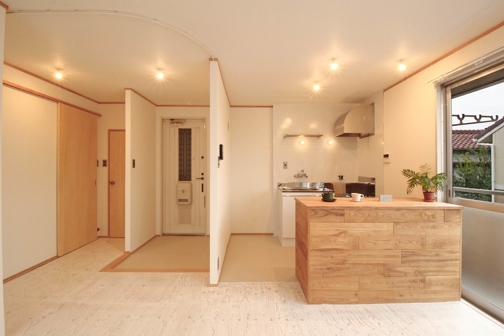 This is an example of a world-inspired kitchen in Other with wood worktops, plywood flooring, an island and white floors.