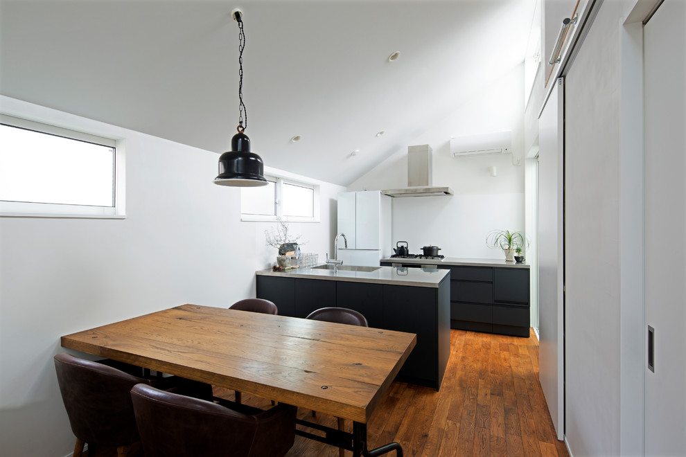 Exempel på ett modernt kök, med en integrerad diskho, släta luckor, vita vitvaror, mellanmörkt trägolv, en köksö, bänkskiva i rostfritt stål, blått stänkskydd och brunt golv
