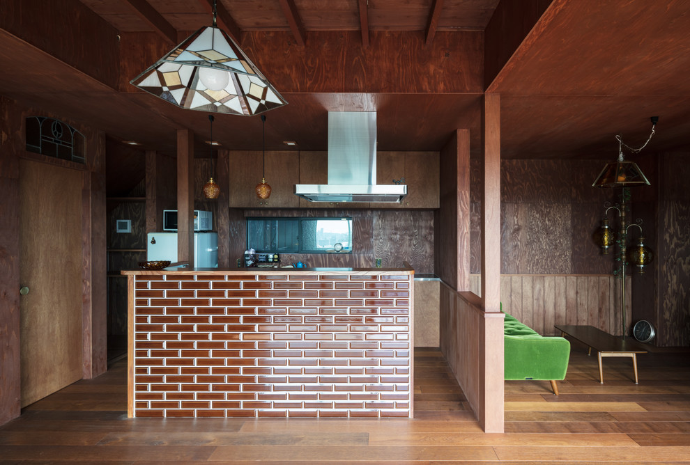 Asiatisk inredning av ett kök med öppen planlösning, med mellanmörkt trägolv, en köksö och brunt golv