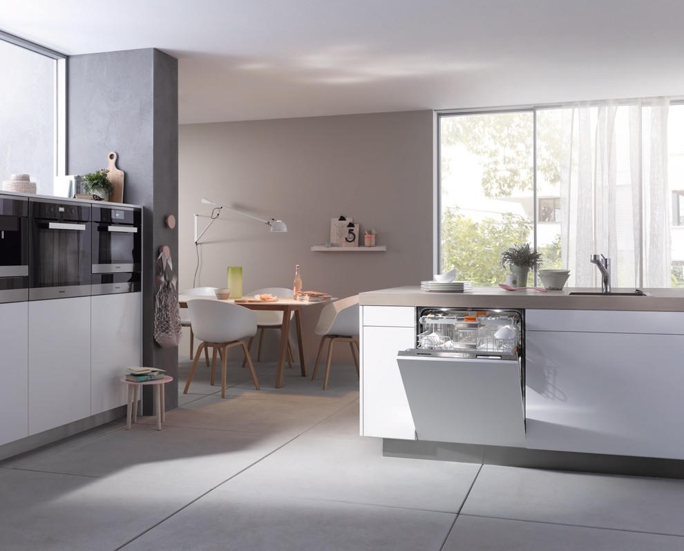 Esempio di un cucina con isola centrale minimal con lavello a vasca singola, ante lisce, ante bianche, pavimento in cemento e pavimento grigio