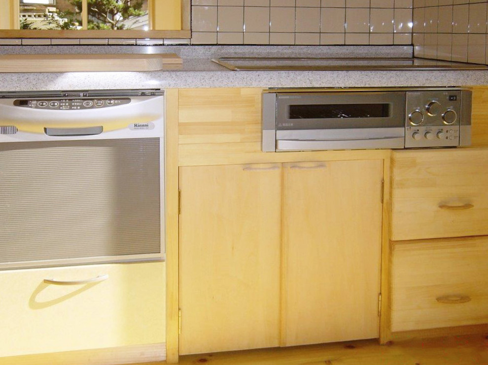 Cette photo montre une cuisine ouverte linéaire en bois clair de taille moyenne avec un évier intégré, un plan de travail en surface solide, une crédence en bois, un électroménager en acier inoxydable et parquet clair.