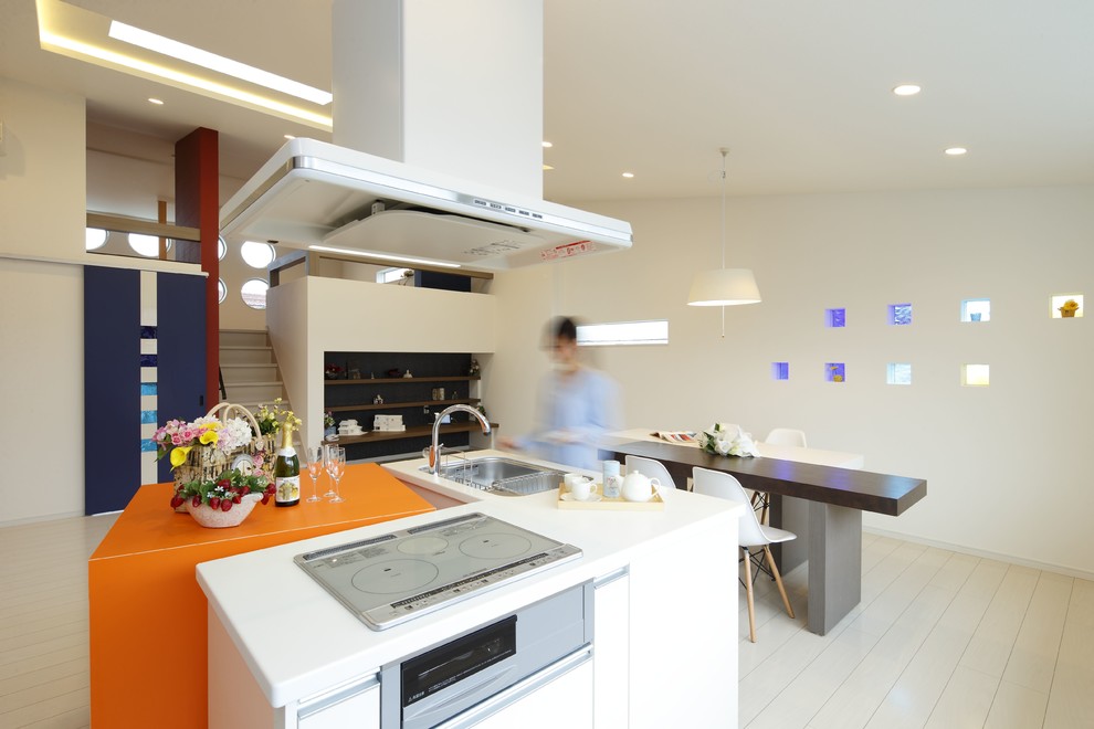 Идея дизайна: большая угловая кухня в современном стиле с обеденным столом, врезной мойкой, деревянным полом, двумя и более островами, белым полом и оранжевой столешницей