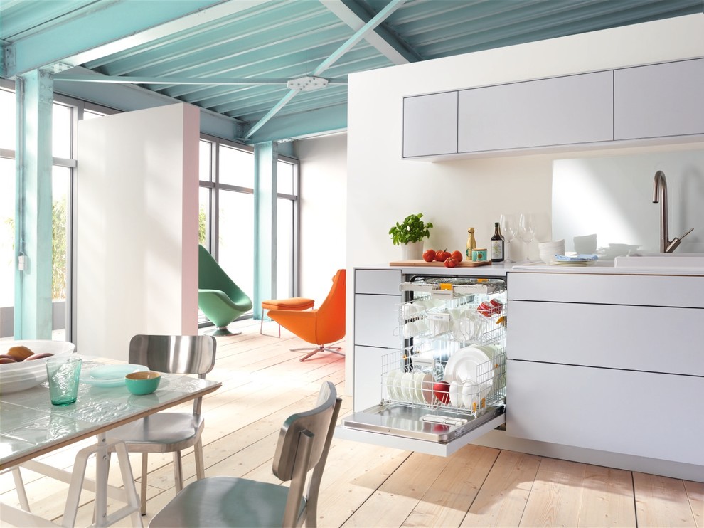 Foto de cocina moderna con armarios con paneles lisos, puertas de armario blancas, salpicadero blanco y suelo de madera clara