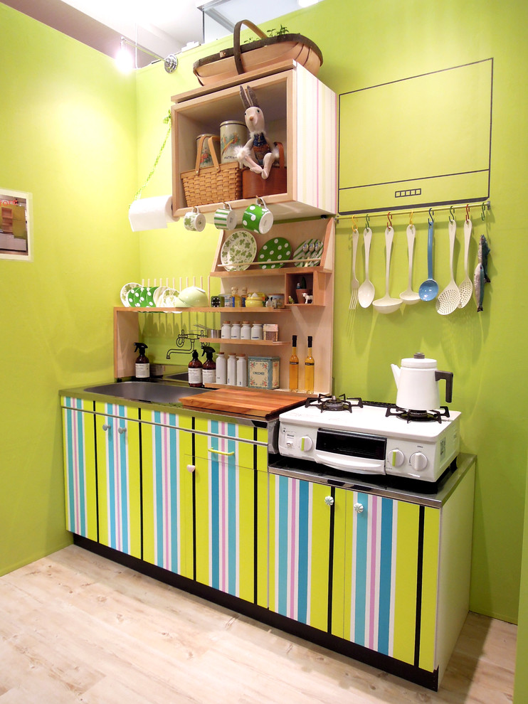 Foto på ett litet skandinaviskt linjärt kök, med en enkel diskho, släta luckor, grönt stänkskydd, ljust trägolv och brunt golv
