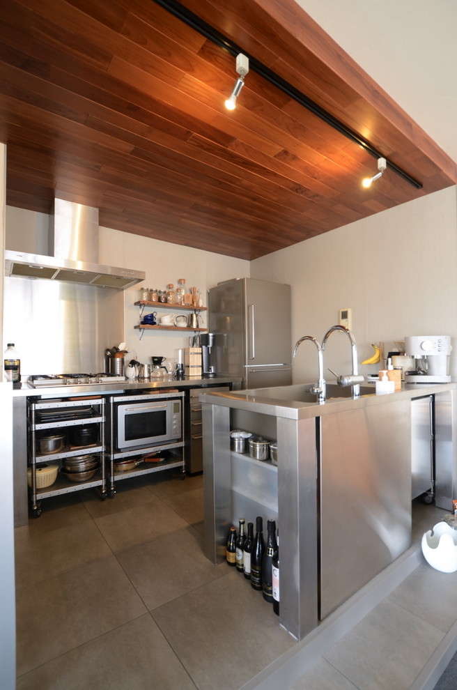 На фото: параллельная кухня среднего размера в стиле лофт с монолитной мойкой, открытыми фасадами, фасадами из нержавеющей стали, столешницей из нержавеющей стали, полуостровом и серым полом