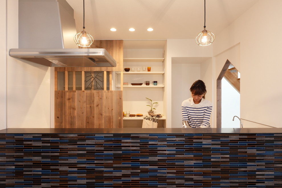 京都にある低価格の小さなラスティックスタイルのおしゃれなキッチン (一体型シンク、インセット扉のキャビネット、白いキャビネット、ステンレスカウンター、青いキッチンパネル、磁器タイルのキッチンパネル、黒い調理設備、無垢フローリング、ベージュの床、グレーのキッチンカウンター) の写真