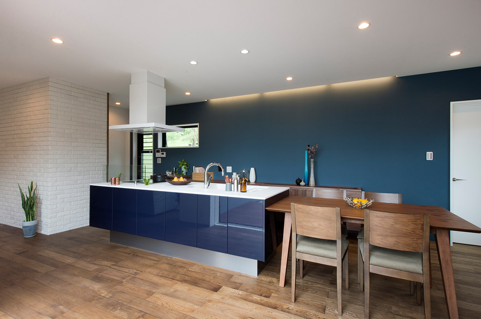 他の地域にあるミッドセンチュリースタイルのおしゃれなアイランドキッチン (フラットパネル扉のキャビネット、青いキャビネット、無垢フローリング、茶色い床) の写真